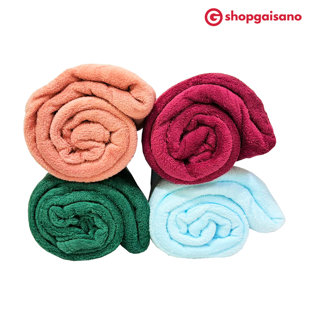 Four rolled plush microfiber blankets in peach, magenta, green, and light blue, arranged in a 2x2 grid on a white background with the ShopGaisano logo in the top right corner.